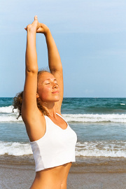 Une jeune femme sur une plage pratique des exercices respiratoires.